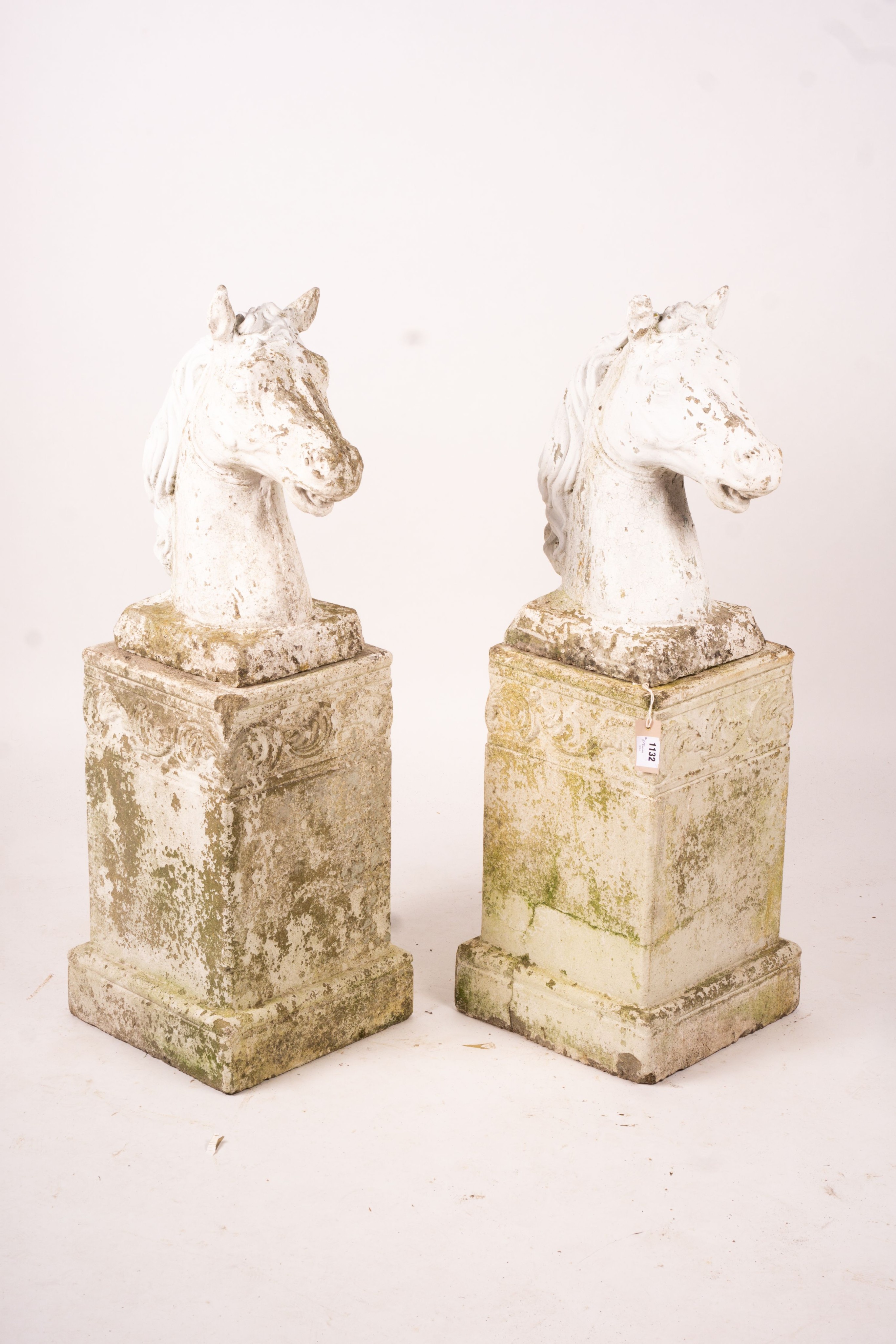 A pair of reconstituted stone horse's heads on plinth bases in the style of Austin and Seeley, height 104cm